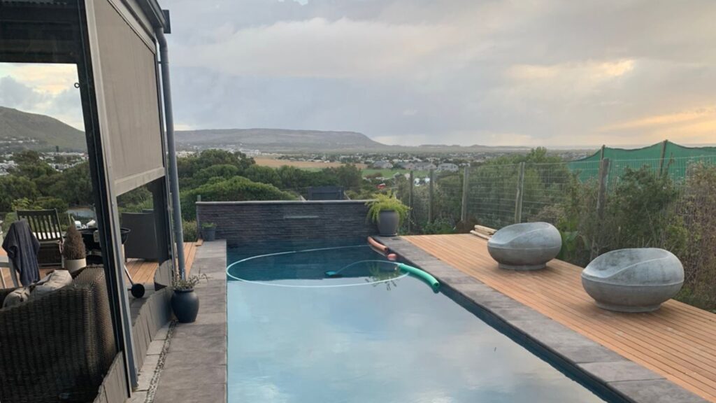 Elevated pool deck with panoramic view, light wood surface, and stone accents.