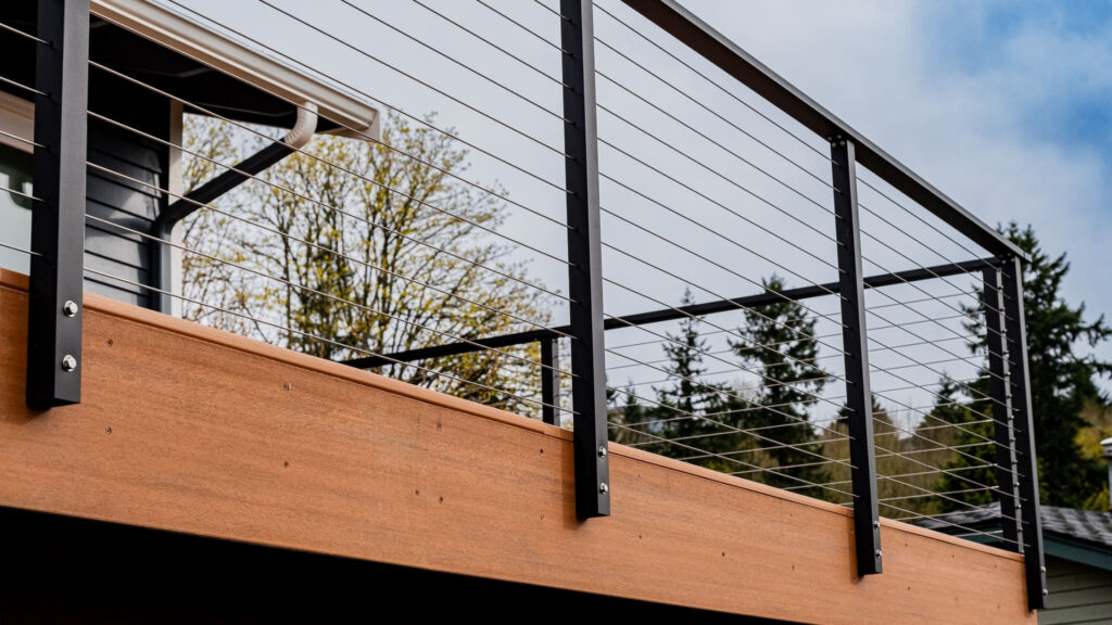 Modern raised deck with black aluminum cable railing and wood fascia, sleek example of cable deck railing ideas.