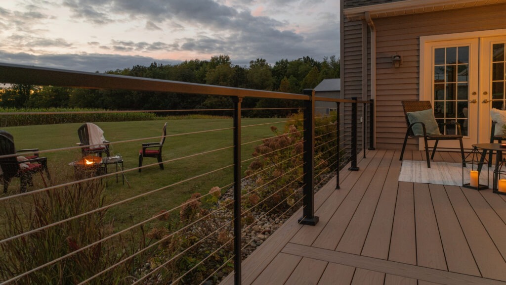 Modern black deck railing with horizontal cables at night.