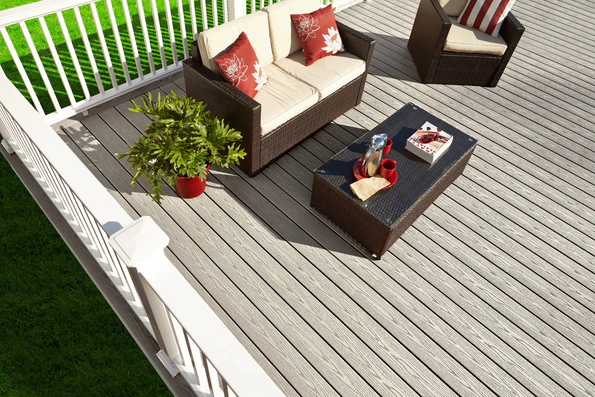 A backyard deck built in the Cottage color, featuring a soft medium-gray tone with a smooth, consistent woodgrain pattern. Outdoor seating and bright accent décor sit on top, showing how the solid gray color works beautifully with a variety of design styles. The deck’s surface appears clean, low-maintenance, and resistant to weathering.
