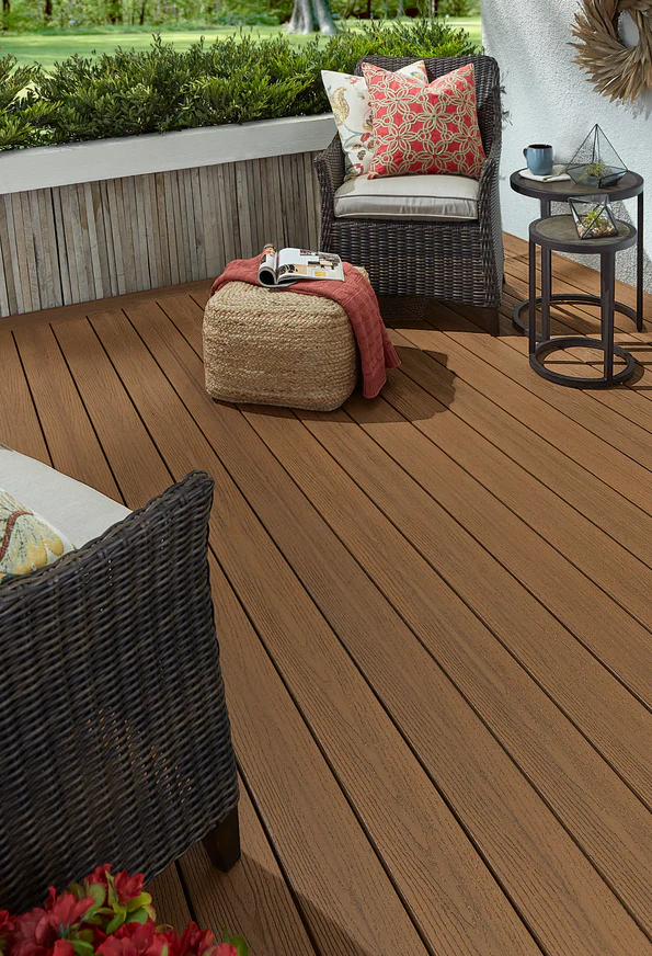 Cozy outdoor seating area installed with Fiberon Good Life Tuscan Villa decking, displaying rich brown tones and natural woodgrain texture under wicker furniture and vibrant accent pillows.