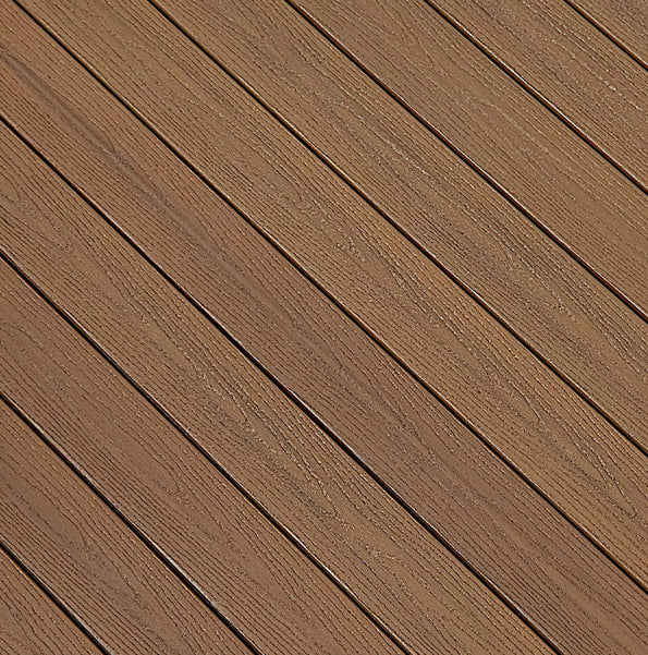 This swatch features Fiberon Good Life Tuscan Villa, a rich, warm brown decking color with multi-tonal streaking that mimics exotic hardwood. The surface blends deeper caramel and golden-brown variations, creating a sun-washed, natural wood look. Its textured grain adds depth and enhances the vibrant, earthy character of the color.