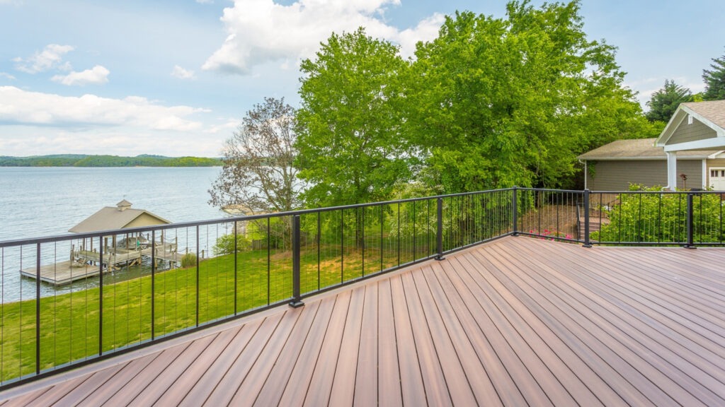 Lakefront deck with black cable railing and panoramic water view.