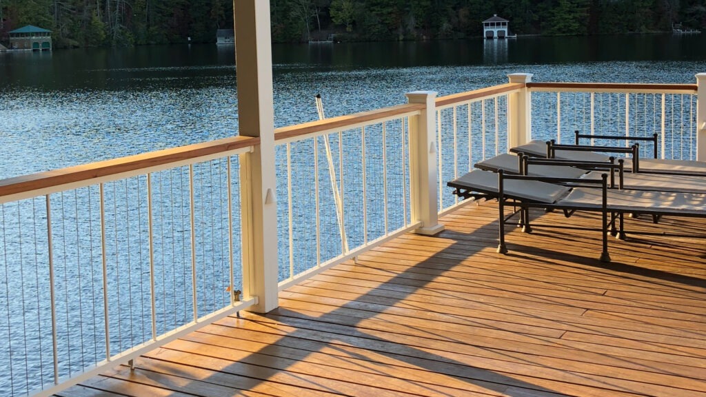 Lakefront deck with white cable railing and wood drink rail.