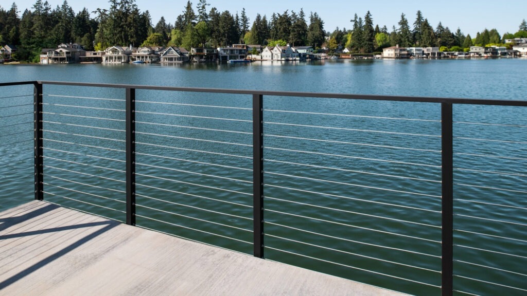 Waterfront deck with black frame and horizontal stainless cable railing.