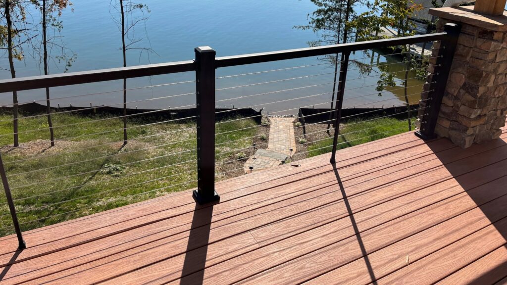 Lakeside deck with dark aluminum cable railing and brown wood decking overlooking water.