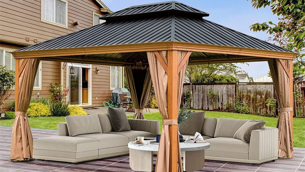 Large gazebo-style pergola with metal roof, beige sectional sofa, curtains, and backyard lawn.