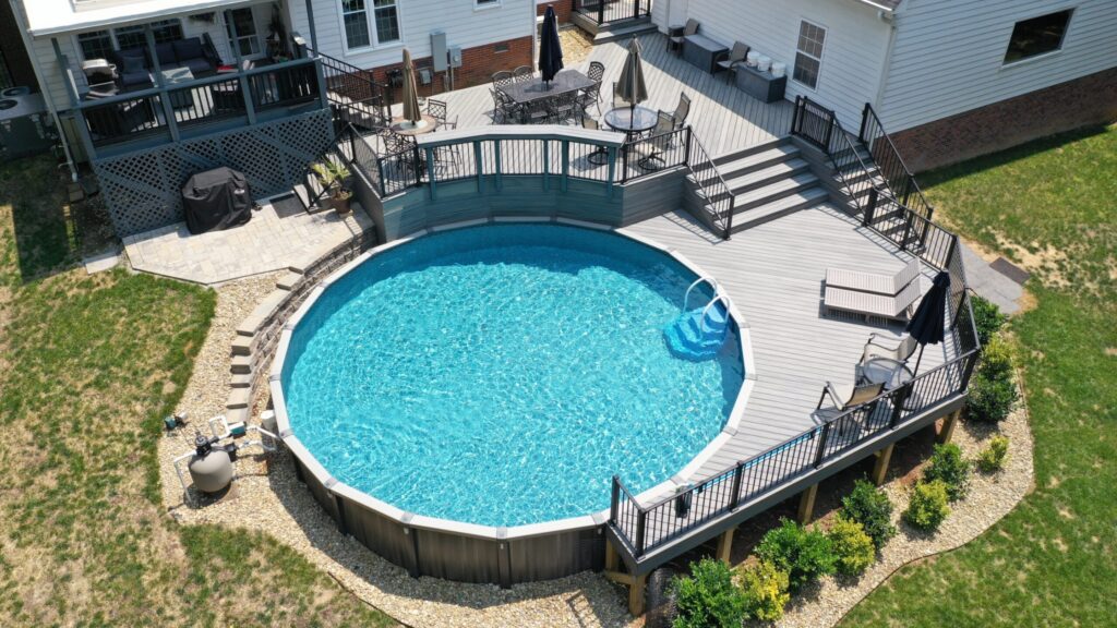 Large round above-ground pool deck with black railings and bright blue water.