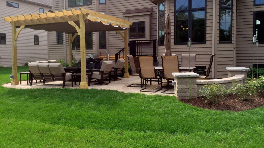 Light wooden pergola with patio chairs, dining table, and backyard lawn.