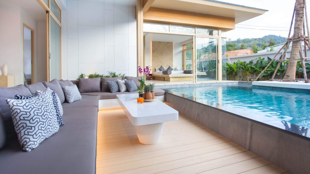 Luxury modern pool deck with outdoor lounge seating and tropical plants.