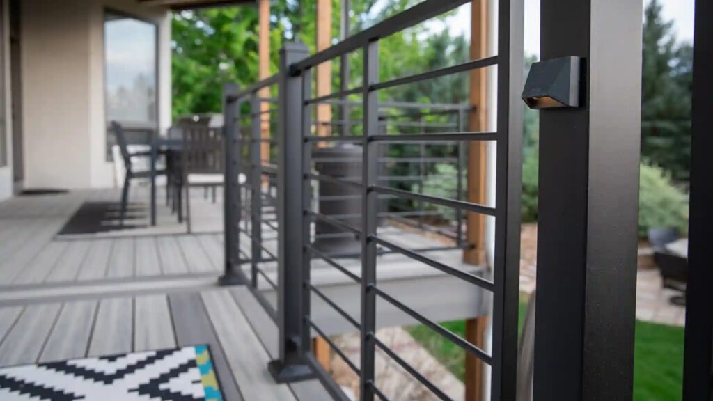 Matte black aluminum horizontal deck railing close-up with gray composite decking.