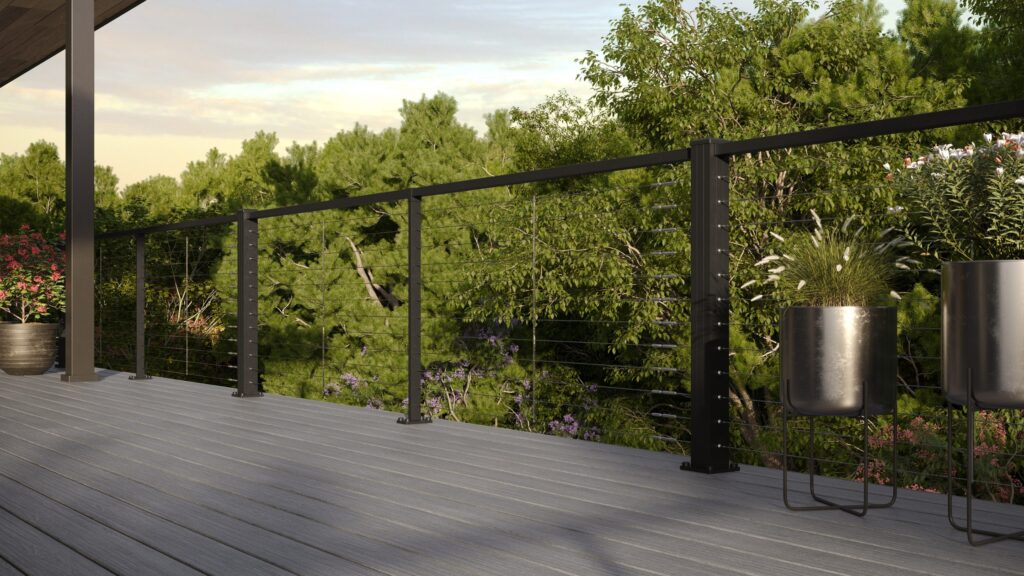 Black aluminum cable deck railing with horizontal lines on gray composite deck surrounded by trees.