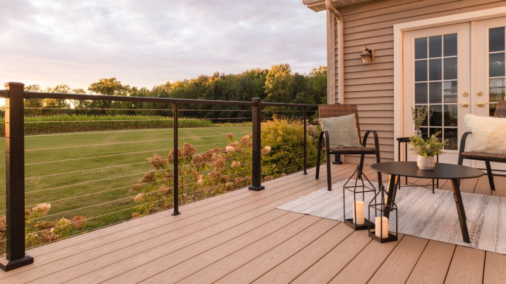 Modern black aluminum horizontal cable deck railing with tan composite decking and outdoor seating.