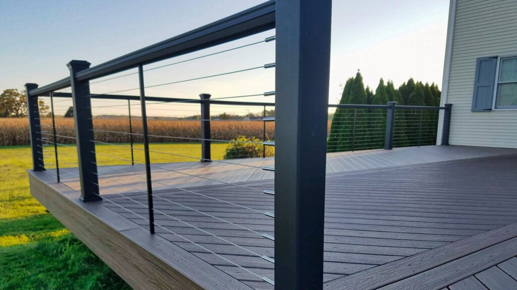Steel cable deck railing on brown composite decking, durable modern outdoor railing setup.