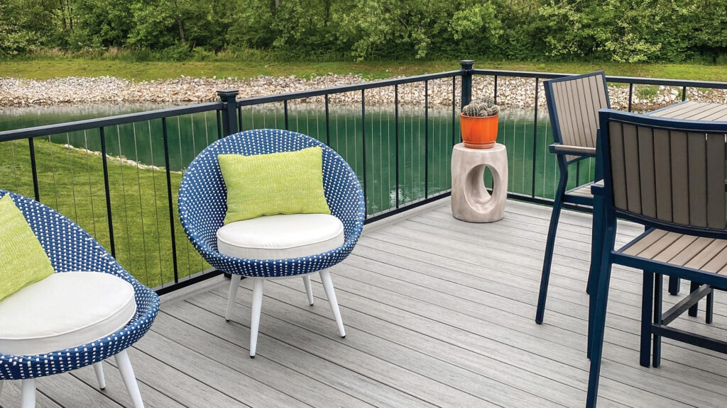 Modern gray deck with vertical black cable railing and lake view in background.