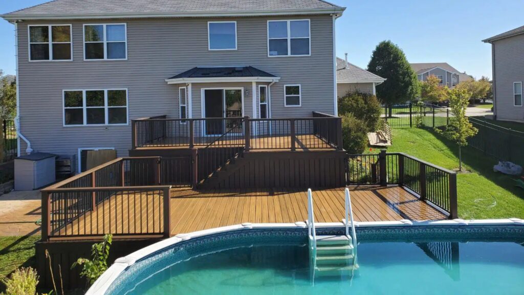 Multi-level backyard pool deck with dark railings and natural wood surfaces.