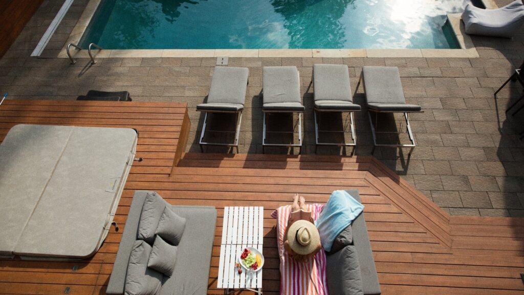 Multi-level wood deck with lounge chairs beside a rectangular inground pool - a standout example of modern inground pool deck ideas.