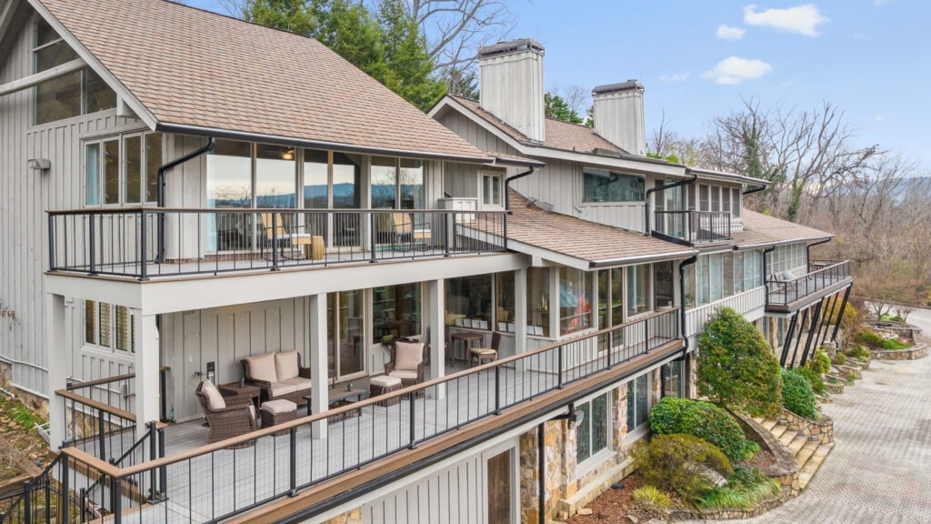 Multi-level home with black cable railing and wood drink rail across balconies.