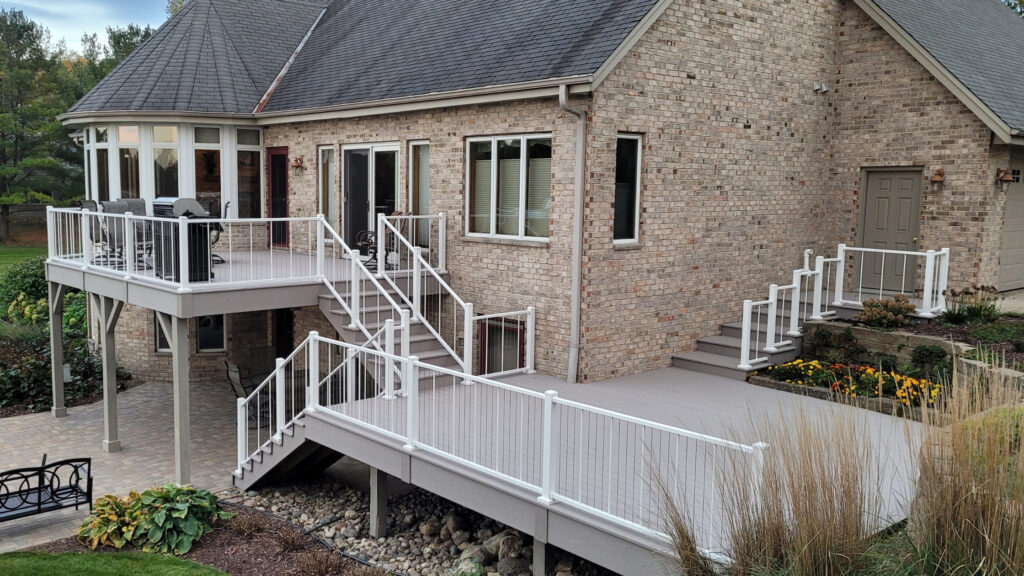 Multi-level composite deck with white cable railing and brick home exterior.