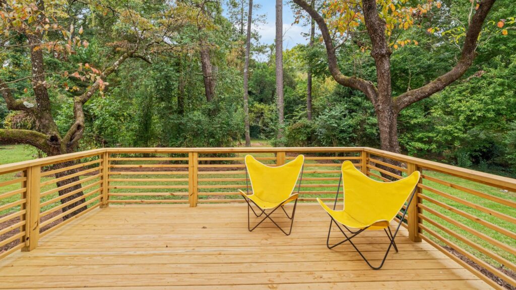 Natural pressure-treated horizontal wood deck railing with forest backyard view.