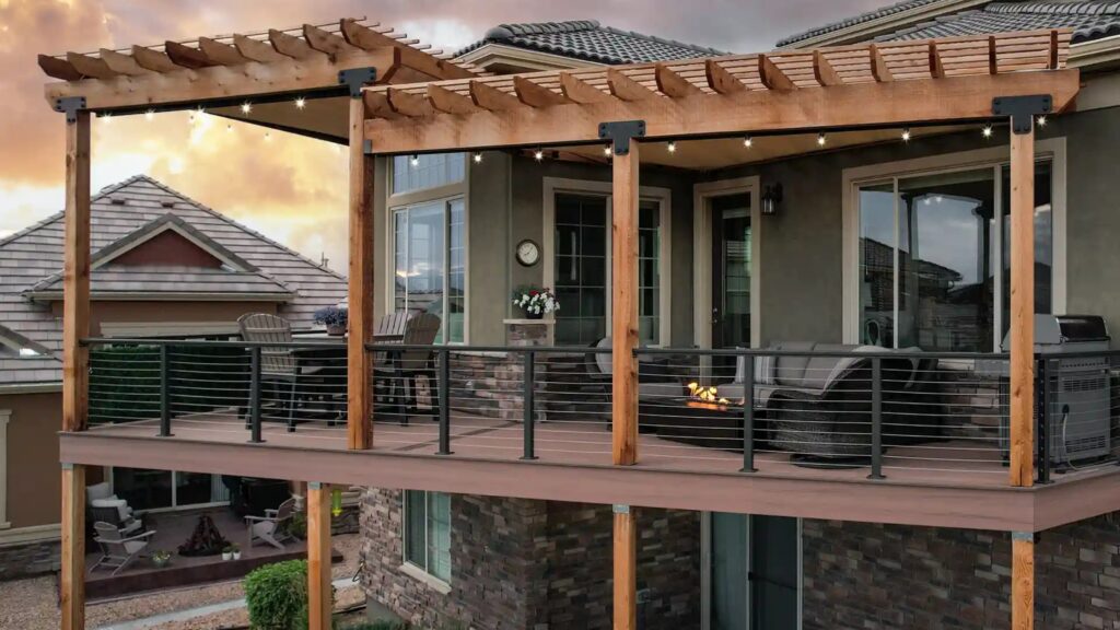 Elevated wood deck with pergola and horizontal black cable railing overlooking backyard.