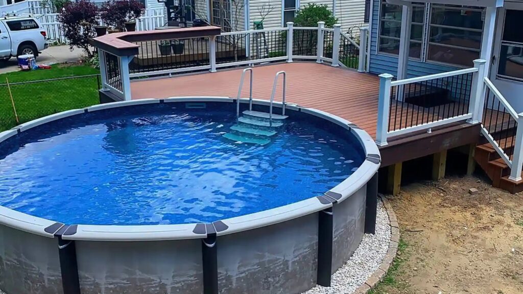 Round above-ground pool surrounded by modern deck with railings and built-in steps.