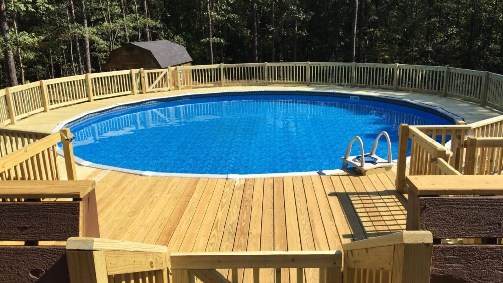 Round wooden above-ground pool deck with full railing and clear blue water.