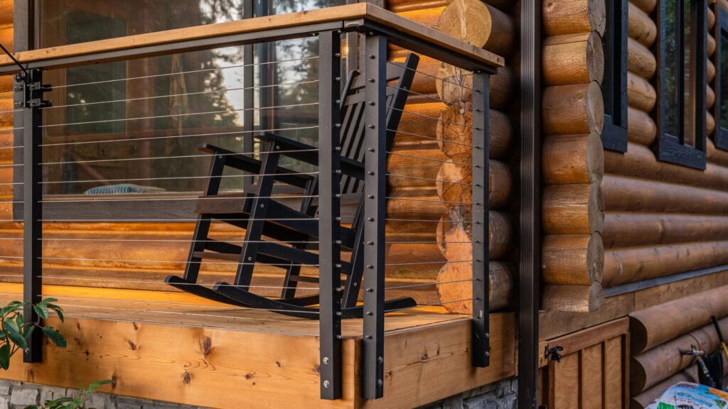 Elevated deck with black aluminum cable railing overlooking mountain landscape and gray composite boards.