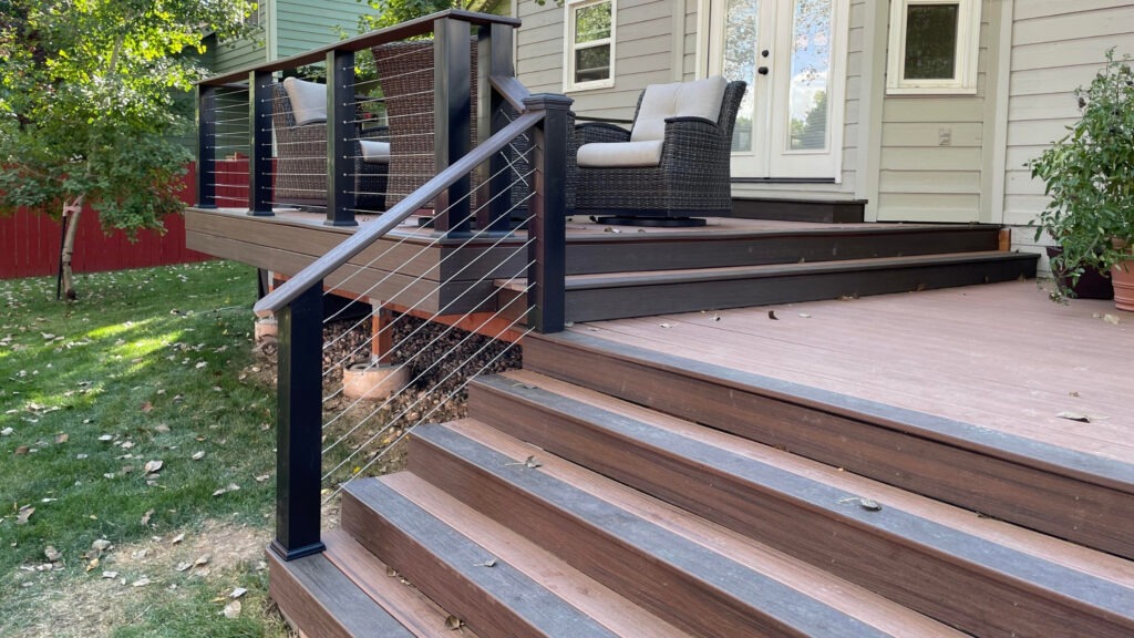 Composite backyard deck with wire cable railing and steps, practical deck cable railing ideas for smaller outdoor areas.