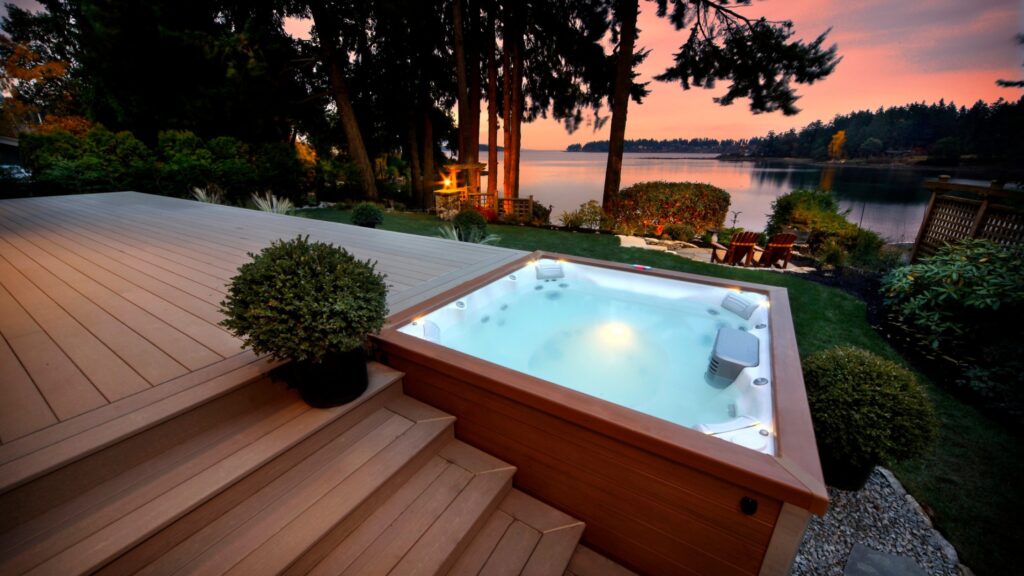 Lakefront sunset deck with built-in hot tub and warm wooden tones.