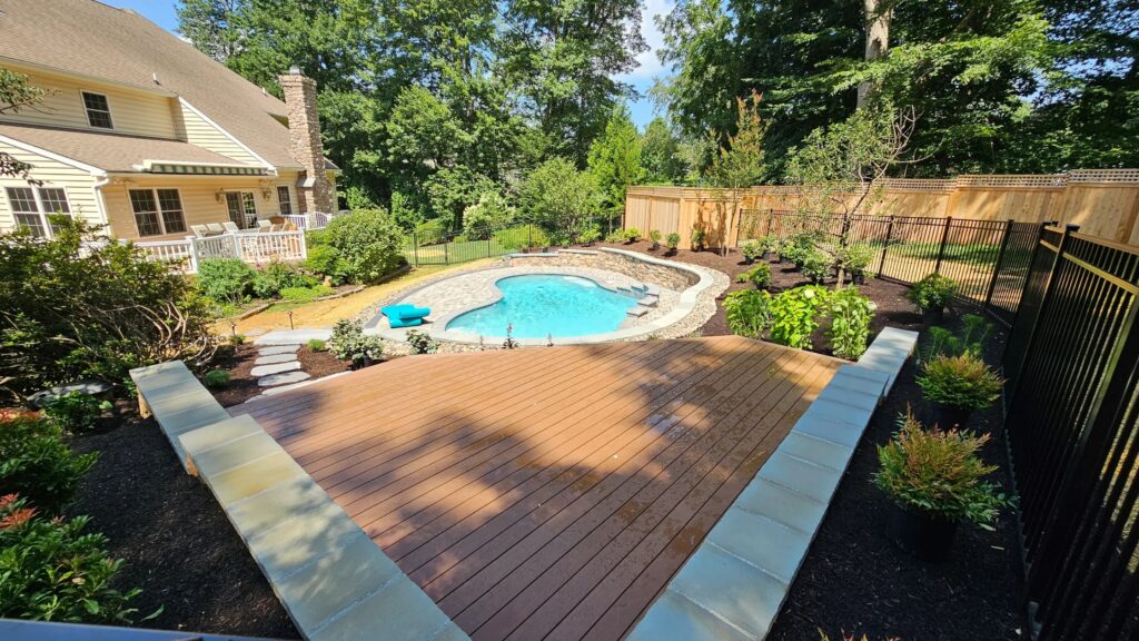 Tiered composite deck overlooking a kidney-shaped stone inground pool.