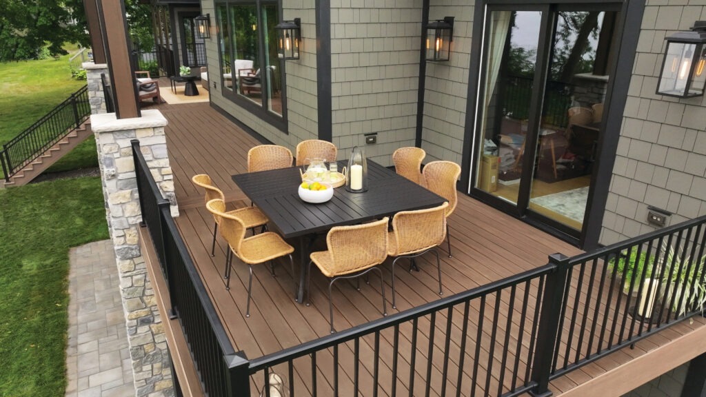 TimberTech English Walnut deck with black metal railing and wicker dining chairs.