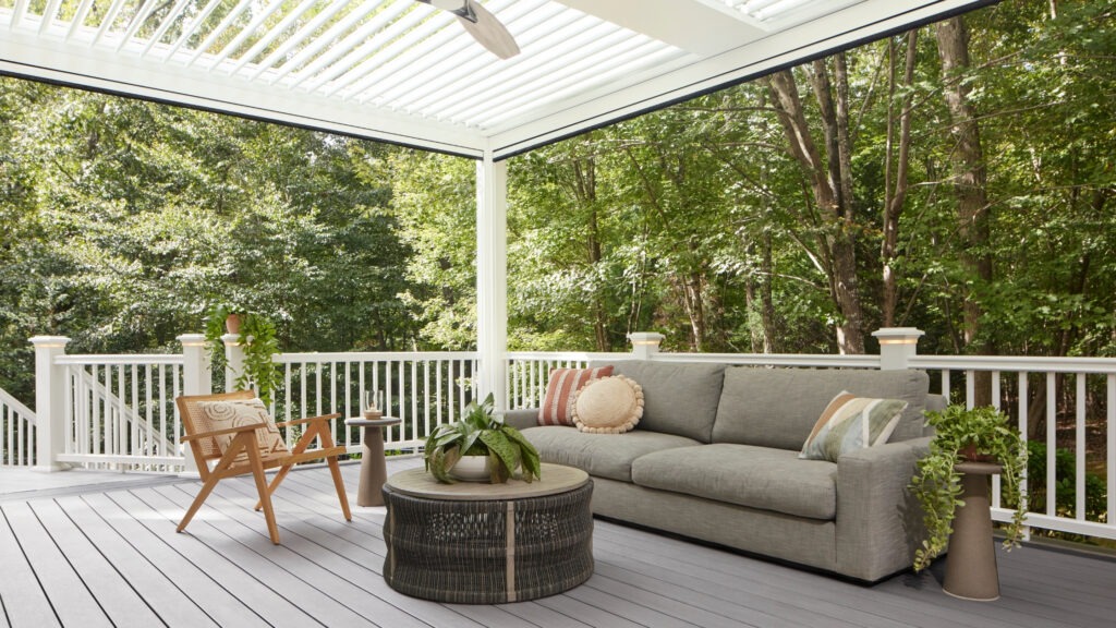 TimberTech Castle Gate deck under white StruXure pergola surrounded by lush greenery.