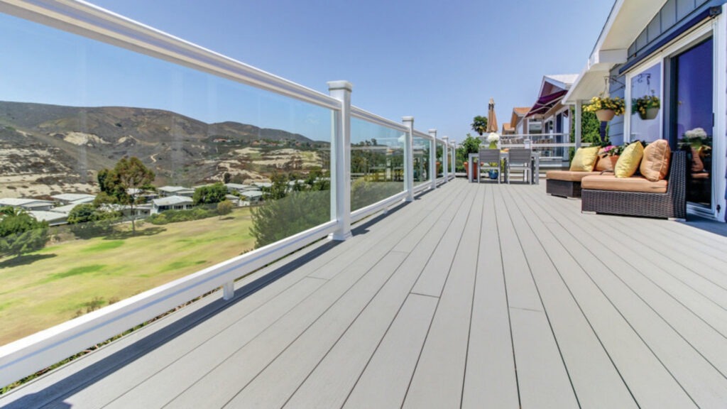TimberTech Terrain Stone Ash deck with glass panel railings and white posts overlooking hillside views.