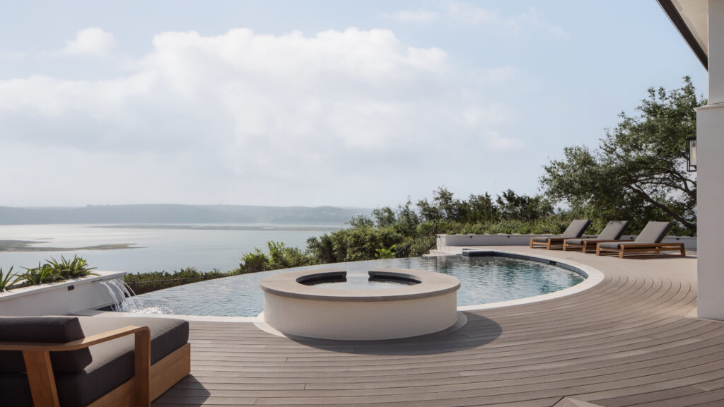 TimberTech Vintage Coastline curved poolside deck with infinity pool and lounge chairs.