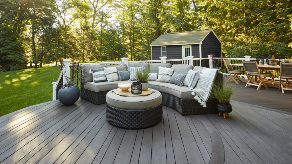 TimberTech Vintage Dark Hickory curved deck with sectional seating and dining area in backyard.