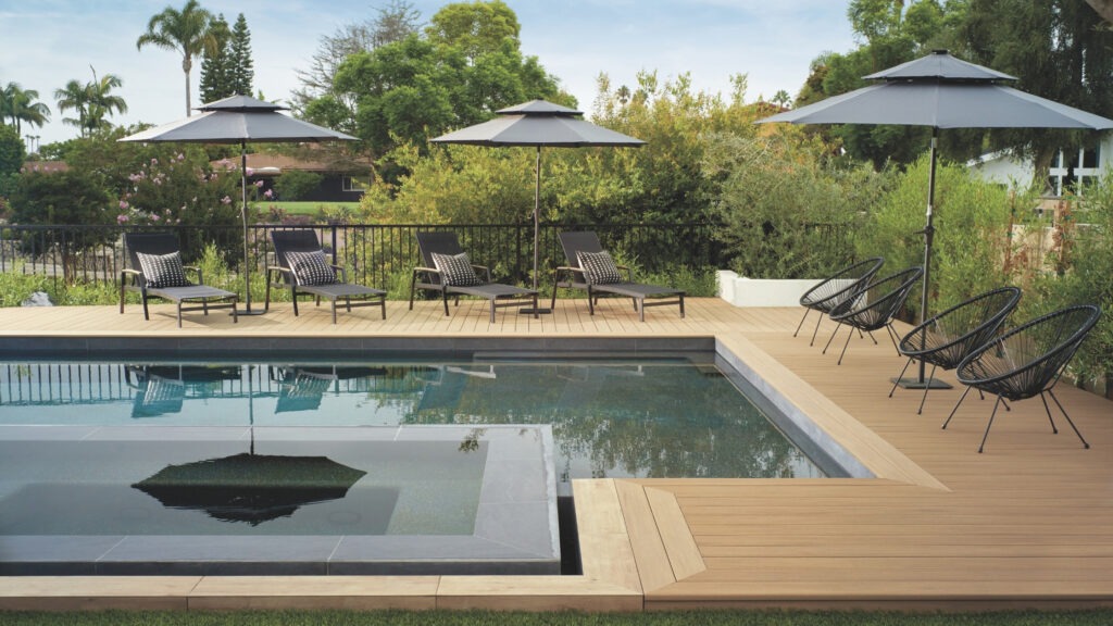 TimberTech Vintage Weathered Teak deck with pool loungers, black umbrellas, and modern rail.