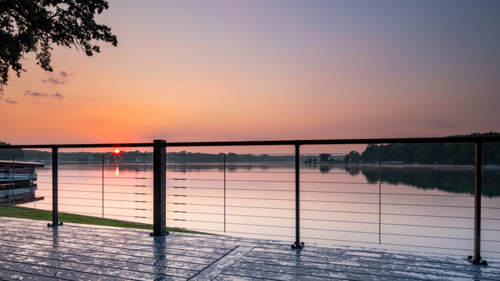 Trex Signature cable railing lakeside deck with sunset reflection, beautiful waterfront cable deck railing ideas.
