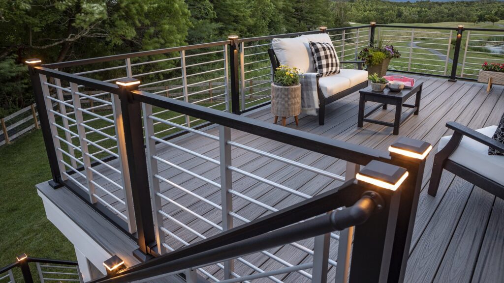 Two-tone horizontal deck railing with post lights on gray composite decking and outdoor lounge seating.