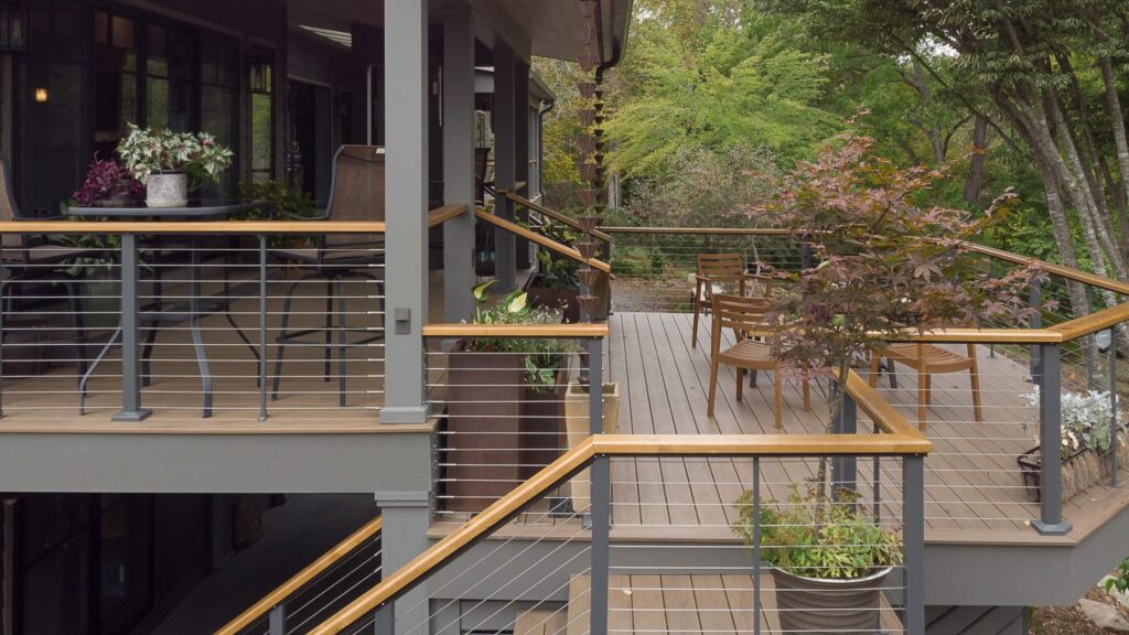 Modern two-tone aluminum and wood horizontal cable deck railing on multi-level composite deck.