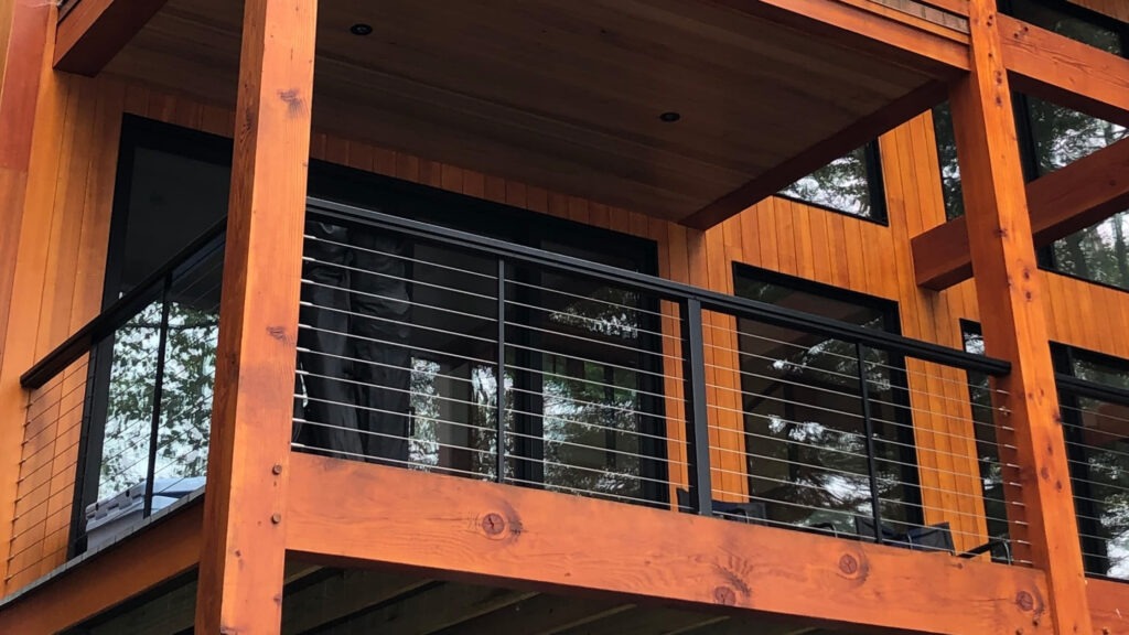 Elevated balcony with wood beams and horizontal cable railing system, stylish example of cable deck railing ideas combining rustic and modern elements.