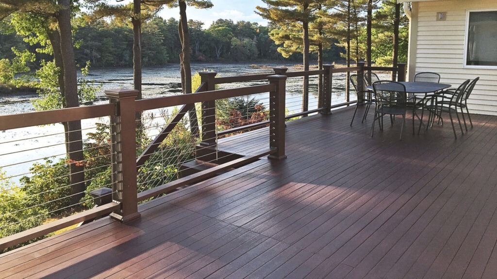 Elevated backyard deck with stainless cable railing and modern furniture, stylish example of cable deck railing ideas for upper-level outdoor living.