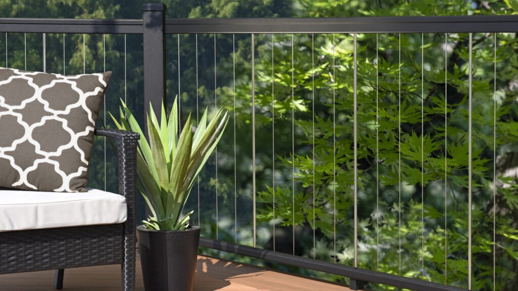Vertical cable deck railing black aluminum frame with outdoor chair and plant, modern example of cable deck railing ideas.