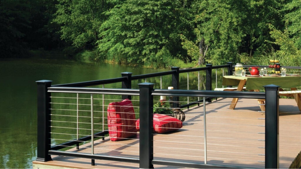 Walnut brown composite deck with stainless cable railing, warm modern outdoor railing design example.