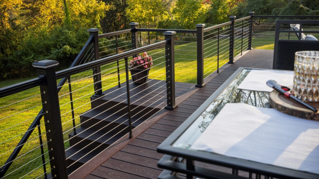 Warm brown deck with black posts and horizontal stainless cable railing at sunset.