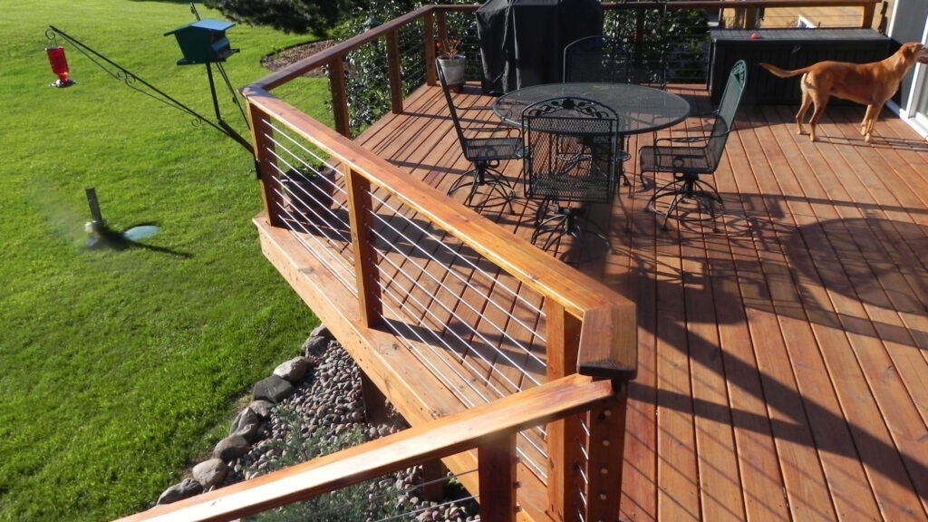 Cozy backyard deck with stainless cable railing and patio furniture, example of cable deck railing ideas for outdoor relaxation.