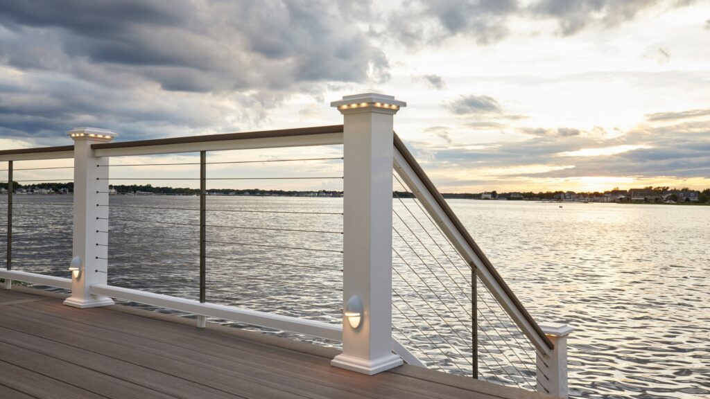 White aluminum cable deck railing with stainless cables and post lights overlooking waterfront.