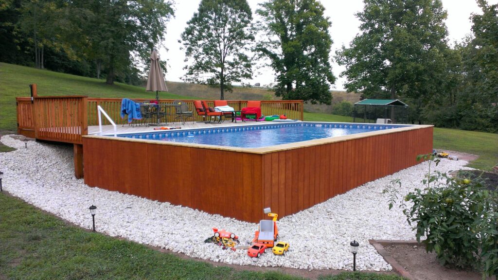 Wooden above ground pool deck with railing, seating area, and natural wood finish.