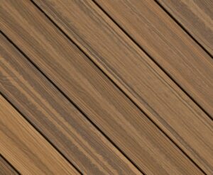 Circular swatch of Envision Distinction Spiced Teak composite decking displaying warm golden-brown tones with subtle darker streaking. The refined wood grain pattern delivers a classic teak-inspired look with modern composite performance.