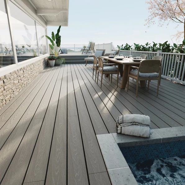 A modern outdoor deck is built with Veranda Stone Gray boards, creating a clean and neutral foundation around a poolside seating area. Natural light enhances the subtle woodgrain texture and soft gray tone. The space feels open, airy, and contemporary, showcasing how the color blends easily with outdoor décor.